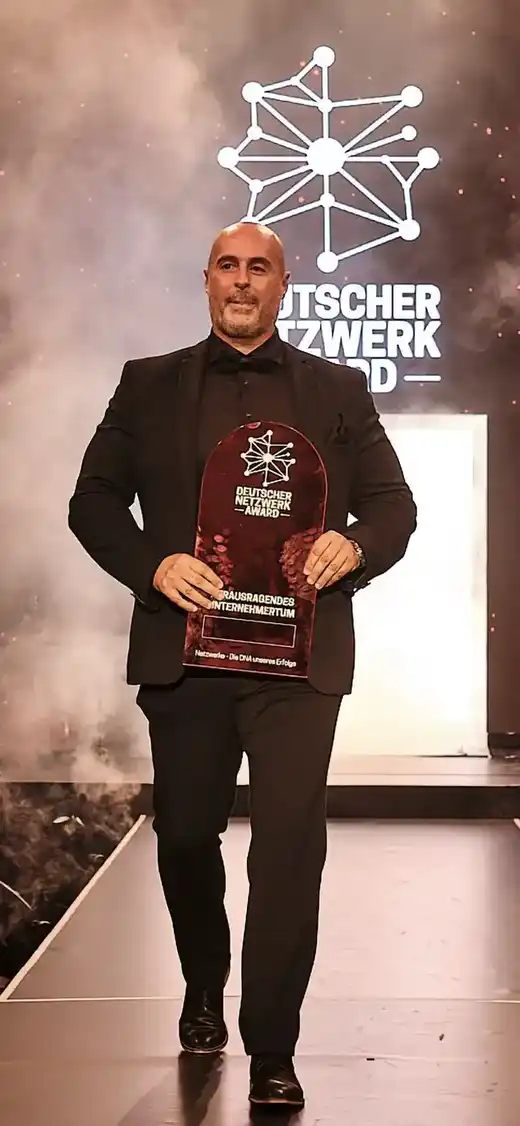 Osvaldo Teixeira auf der Bühne des Deutschen Netzwerk Awards 2025 mit der Trophäe